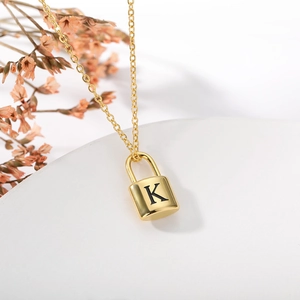 Detail of a gold padlock pendant necklace featuring an engraved letter K decoration