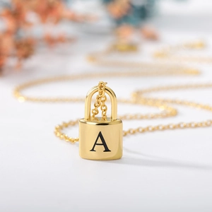 Macro shot of gold stainless steel padlock pendant with letter A engraving on fine chain