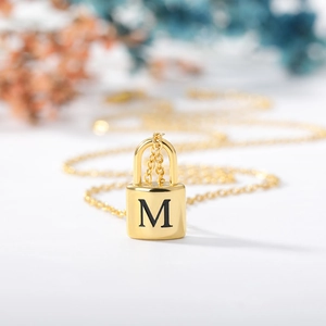 Detailed view of a gold padlock pendant necklace featuring an engraved letter M on an O-chain