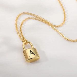Detailed macro view of gold padlock pendant with letter A engraving on fine link chain