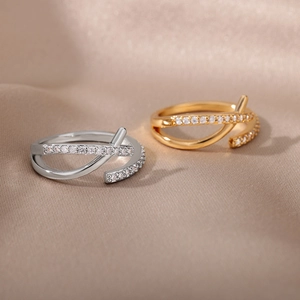 Eleganti anelli incrociati color oro e argento con zirconi su sfondo di seta morbida