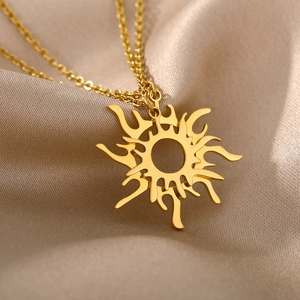 Detailaufnahme des goldenen Edelstahl-Sonnenanhängers auf champagnerfarbenem Seidenstoff