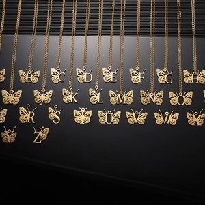 Macro shot of gold-plated butterfly letter pendants on cross chains with hollow design