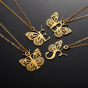 Détails macro des pendentifs lettre papillon ajourés dorés sur chaînes à maillons fins