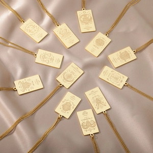 Vista plana de doce collares de tarot zodiaco en acero dorado 18K sobre seda champán