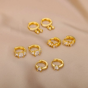 Nahaufnahme von 18k vergoldeten Huggie-Ohrringen mit Schmetterling-Kreuz und Zirkon-Steinen