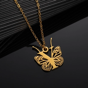 Macro detail of gold stainless steel butterfly necklace pendant featuring the letter V