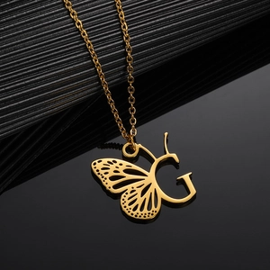 Macro shot of gold stainless steel butterfly wing integrated with capital letter G pendant