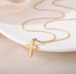 Détail du collier croix en acier inoxydable doré avec bordure perlée sophistiquée