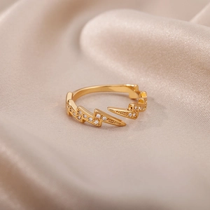 Dettaglio macro dell'anello a fulmine dorato con zirconi bianchi su seta