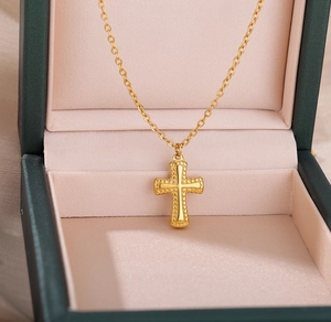 Macro de collier croix dorée avec bordure perlée dans une boîte à bijoux élégante