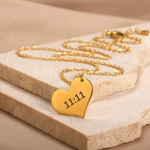 Detailed macro view of gold heart pendant necklace featuring 11:11 engraving on stone stand
