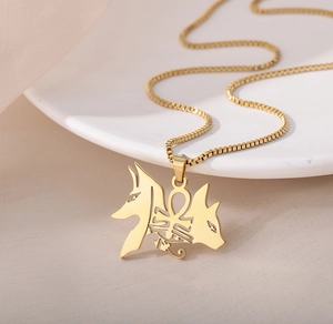 Vue macro du pendentif égyptien Ankh doré et Anubis avec une chaîne à mailles carrées