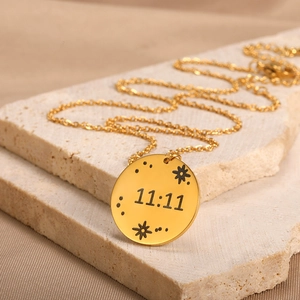 Detail view of gold 11:11 angel number rectangle pendant necklace on stone texture
