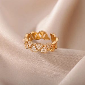 Dettaglio macro di un anello a nido d'oro con pavé di zirconi su seta color champagne