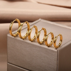 Three pairs of minimalist 18k gold plated hoop earrings in various sizes on silk