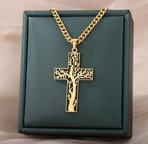Vue détaillée d'un pendentif croix dorée avec un motif ajouré d'Arbre de Vie ciselé