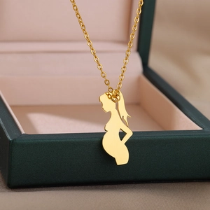 Golden pregnant silhouette pendant necklace on a green jewelry gift box background