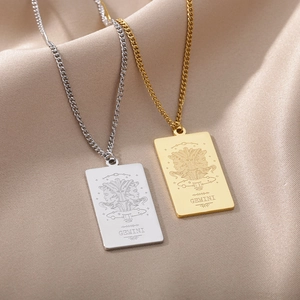 Detalle de colgantes de Géminis en oro y plata sobre una suave tela de seda
