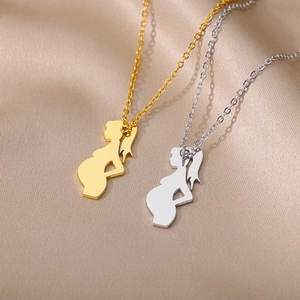 Macro shot of gold and silver mother-to-be silhouette pendants on satin fabric