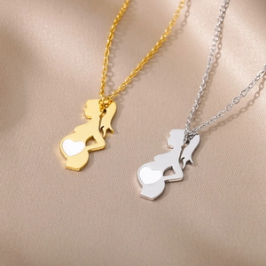 Close-up of gold and silver pregnancy silhouette pendants with heart inlay details