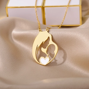 Close-up of golden mother and child pendant with white heart on champagne satin background