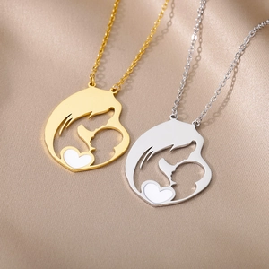 Close-up of mother and child silhouette pendant in gold and silver finish with heart detail