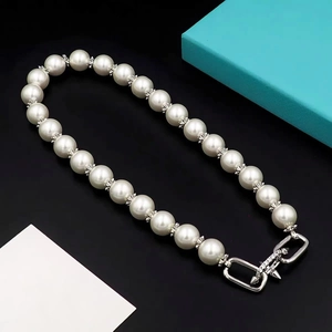 Macro detail of pearl necklace with pavé spacers and interlocking rectangular clasp
