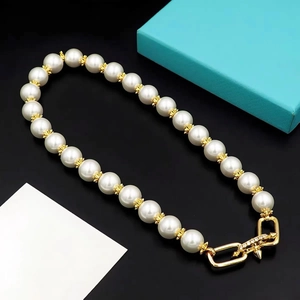 Macro detail of U-shaped gold clasp with zircons and pearls on bullet rivet necklace