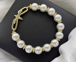 Macro detail of pearl bracelet with gold geometric beads and sparkling star pendant