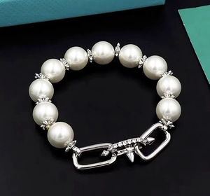 Close-up of pearl bracelet with bullet studs and zircon accents on a blue background