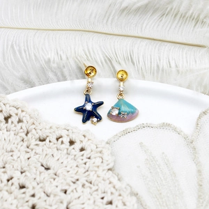 Detailed macro view of asymmetric starfish and seashell earrings with zircon accents