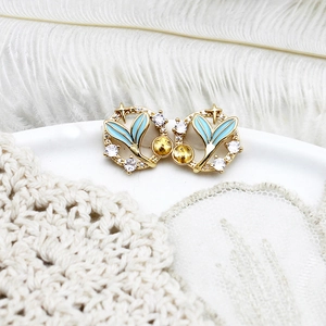 Macro detail of mermaid tail earrings with blue enamel and sparkling white cubic zirconia