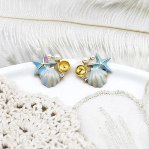 Macro shot of sea star and shell earrings with white pearls and sparkling rhinestones