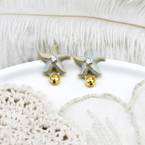 Blue enamel starfish earring mount with gold accents and cubic zirconia on a white feather