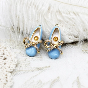 Macro view of light blue ballet shoe pendant with gold bow and sparkling crystal inlay