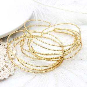 Dettaglio macro di bracciali rigidi aperti placcati oro 18K con finitura scintillante