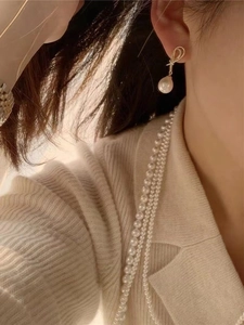 Dettaglio orecchino a fiocco in oro 18K con perla e collana di perle a più strati