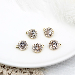 Detail of five gold-plated brass pendants with round zircons on a white ceramic plate