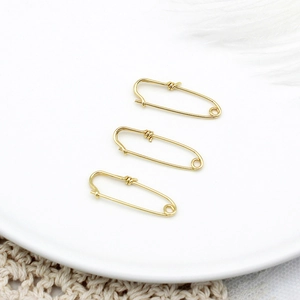 Detailed view of three 18K gold plated safety pin pendants with fine wire wrap decoration