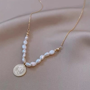 Detailed macro view of an 18K gold coin pendant with baroque pearl beads on silk