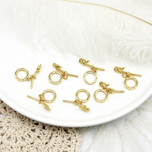 Detail van zeven sets gouden zirkonia toggle sluitingen in een witte keramische schaal