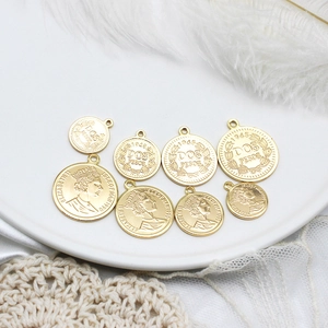 Macro view of gold-plated 18K Elizabeth II and Mexican peso coin charms for DIY jewelry