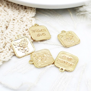 Detailed macro view of five 18K gold plated square pendants with rose flower carvings