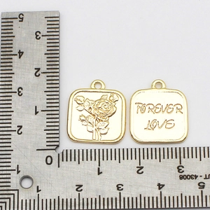 Detail of square 18K gold plated pendants featuring rose relief and Forever Love engraving