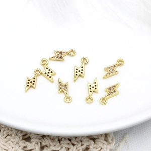 Macro shot of 18K gold plated lightning charms with zircon inlay on a white plate