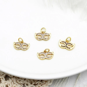 Macro view of four 18K gold-plated mask charms with micro-pave white zircon for DIY jewelry