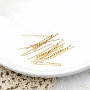 Vista macro di spilli a T placcati in oro 18K per gioielli su un piatto di ceramica bianca