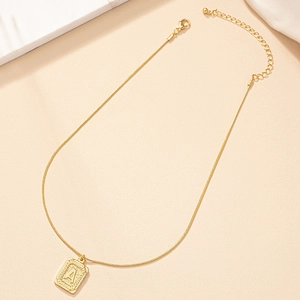 Close-up of golden letter A square pendant necklace with intricate relief texture details