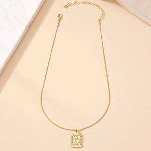 Golden necklace with square letter A pendant and snake chain on marble backdrop
